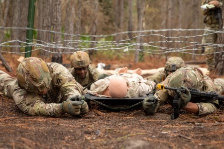 Soldiers from the 3rd Infantry Division low crawl with a simulated casualty for the Expert Field Medical Badge on Fort Stewart, Georgia, Jan. 18, 2023. In order to earn the badge candidates must complete a written test, a physical fitness assessment, day and nighttime land navigation courses, various warrior skills, tactical combat casualty care, evacuation lanes, a 12-mile foot march and disassemble, reassemble and function check their M4 riles; validating themselves as Army medical professionals and distinguishing themselves amongst their peers. 